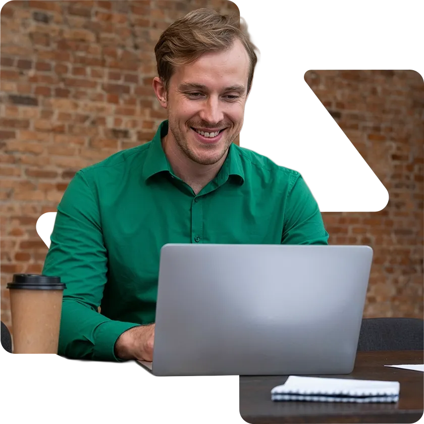 Pessoa sorrindo usando laptop, simulando crédito pessoal Quita